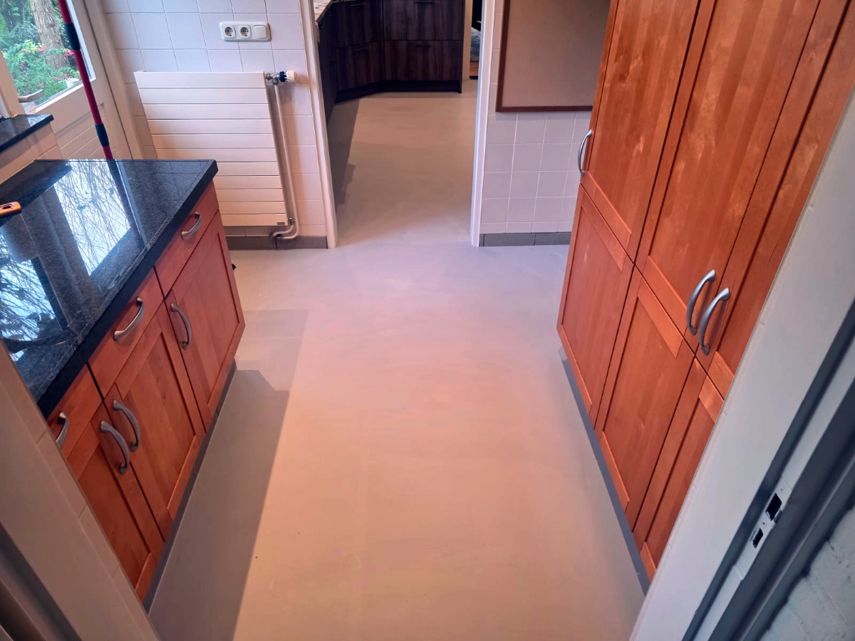 Strakke en onderhoudsvriendelijke microcementvloer in bijkeuken met naadloze betonlook afwerking door NM Gietvloeren in Zwijndrecht
